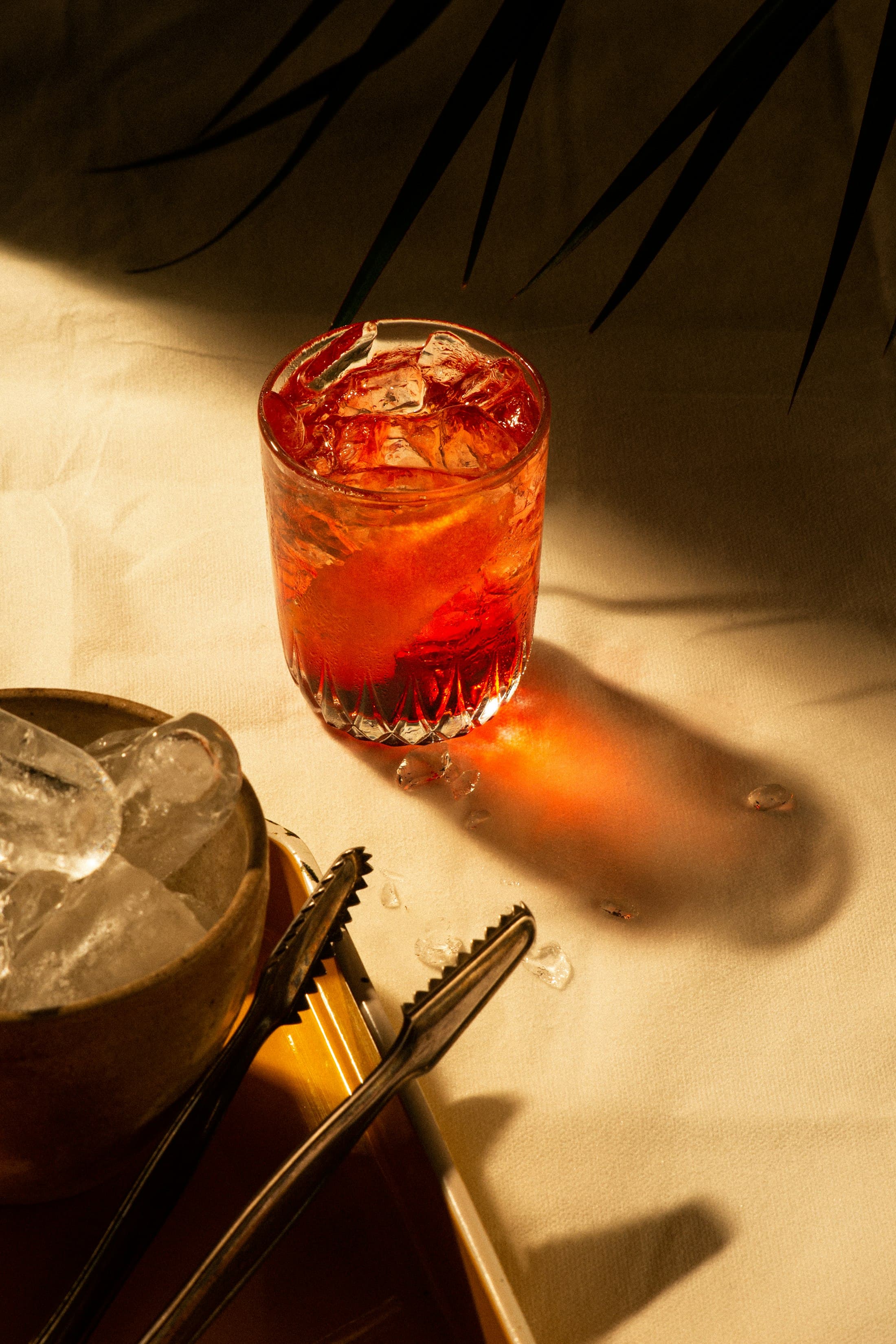 Roter Cocktail mit Eis im Kristallglas im warmen Licht